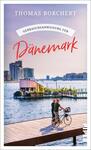 Das Buchcover zeigt einen malerischen Ausblick auf einen Hafen mit modernen Gebäuden im Hintergrund. Im Vordergrund sind ein Paar und ein Radfahrer auf einem Holzsteg abgebildet. Der Himmel ist klar und in sanften Farbtönen, die eine entspannte Atmosphäre erzeugen. Der Titel „Gebrauchsanweisung für Dänemark“ ist in großen, roten Buchstaben platziert, während der Autor „Thomas Borchert“ oben in eleganter Schrift erscheint.