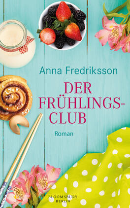 Der Frühlingsclub Das Buchcover zeigt einen leicht strukturierten, hellblauen Holzhintergrund. Im oberen Bereich steht in großen, roten Lettern der Titel „DER FRÜHLINGS-CLUB“ und darunter der Schriftzug „Roman“ in kleinerer Schrift. Daneben sind frische Erdbeeren und schwarze Beeren in einer weißen Schüssel abgebildet, während ein Glas Milch, ein Zimtschneckengebäck und ein grüner Stoff mit blühenden, rosa Blumen harmonisch platziert sind. Farbige Essstäbchen ergänzen die Szenerie und verleihen dem Cover eine fröhliche, einladende Atmosphäre.