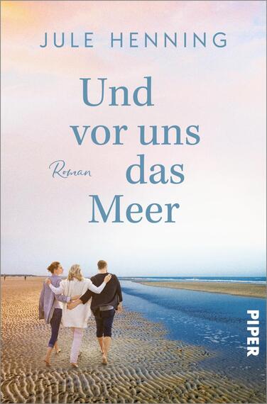 Das Buchcover zeigt eine Strandlandschaft bei Sonnenuntergang. Im Vordergrund gehen drei Personen nebeneinander, die sich an den Händen halten. Die sanften Pastelltöne des Himmels reichen von Blau zu Rosa, während der Sand in warmen Beigetönen erstrahlt. In der Mitte des Covers steht der Titel „Und vor uns das Meer“ in einer eleganten, hellblauen Schrift, darunter ist „Roman“ in kleinerer Schriftart platziert. Oben ist der Name der Autorin, Jule Henning, zu sehen.