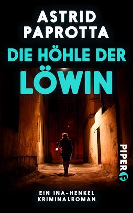 Die Höhle der Löwin Das Buchcover zeigt einen dunklen, schmalen Straßenabschnitt, der von hohen Gebäuden flankiert wird. Eine schwarz gekleidete Person mit umgedrehter Kapuze steht im Vordergrund und blickt in die Gasse. Der Titel „DIE HÖHLE DER LÖWIN“ ist in kräftigem Türkis hervorgehoben, während der Autorenname „ASTRID PAPROTTA“ in weißer Schrift darüber platziert ist. Unten rechts befindet sich das Logo des Verlags Piper in blau. Die gesamte Atmosphäre vermittelt Spannung und Geheimnis.