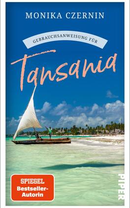 Gebrauchsanweisung für Tansania Das Buchcover zeigt eine paradiesische Küstenlandschaft mit klarem, türkisfarbenem Wasser und weißem Sandstrand. Im Vordergrund segelt ein traditionelles Boot mit weißem Segel, während im Hintergrund sanfte Wellen und eine grüne Uferlandschaft zu sehen sind. Der obere Bereich wird von einem blauen Himmel und einigen Wolken dominiert. Der Titel „Gebrauchsanweisung für Tansania“ ist in einer auffälligen, orangefarbenen Schrift gestaltet. Oben links steht der Name der Autorin „Monika Czernin“, während das Label „SPIEGEL Bestseller-Autorin“ unten in einem roten Quadrat hervorgehoben ist.