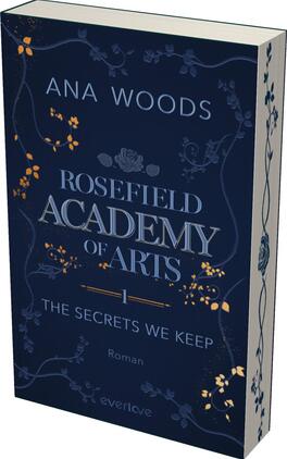 Rosefield Academy of Arts – The Secrets We Keep Das Buchcover zeigt einen tiefblauen Hintergrund, der mit filigranen floralen Mustern in Creme und Gold verziert ist. Oben befindet sich der Autorname „ANA WOODS“ in hellem, eleganten Schriftzug. In der Mitte ist der Titel „ROSEFIELD ACADEMY of ARTS“ in markanter, größerer Schrift dargestellt, darunter der Untertitel „THE SECRETS WE KEEP“ in kleinerer, aber ebenfalls gut lesbarer Schrift. Am unteren Rand steht das Wort „Roman“ in schlichtem Font. Die Atmosphäre des Covers vermittelt ein geheimnisvolles und künstlerisches Ambiente.