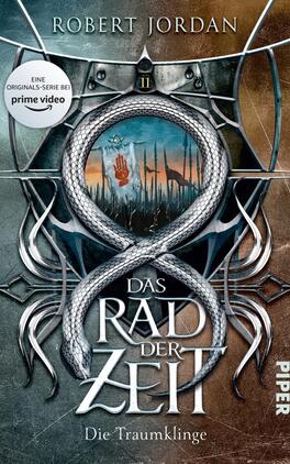 Das Rad der Zeit 11. Das Original Das Buchcover zeigt einen stilisierten Schlangenring, der sich um einen blauen, runden Hintergrund windet, auf dem eine Hand und eine rote Blutflecken sichtbar sind. Im oberen Bereich ist der Titel „Das Rad der Zeit“ in großer, weißer Schrift platziert, darunter der Untertitel „Die Traumklinge“. Der Hintergrund hat eine düstere, geheimnisvolle Atmosphäre, mit angedeuteten dürren Bäumen und einem hellen Himmel, der an einen Sonnenuntergang erinnert. Oben links befindet sich ein Hinweis auf die Primetime-Serie.