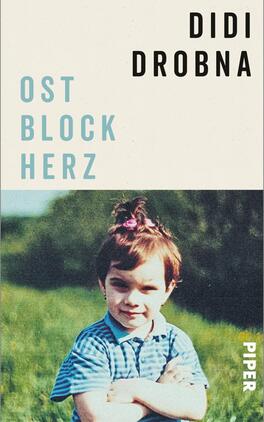 Ostblockherz Das Buchcover zeigt ein nostalgisches Bild eines Kindes mit braunen Haaren und einem Zopf, das auf einer grünen Wiese posiert. Das Kind trägt ein blaues, gestreiftes Hemd und schaut direkt in die Kamera. Im oberen Bereich des Covers ist der Name des Autors „Didi Drobna“ in großen, schwarz gefärbten Buchstaben platziert. Darunter befindet sich der Titel „OST BLOCK HERZ“ in hellblauen, größeren Lettern. Die Hintergrundfarbe ist hell und unifarben, was die Schriftzüge betont und eine einladende Atmosphäre schafft.