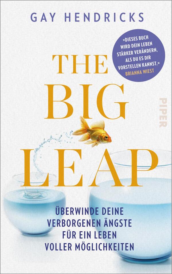 Das Buchcover zeigt einen hellen, minimalistischen Hintergrund. In der Mitte befindet sich der Titel „THE BIG LEAP“ in großen, gelben Buchstaben. Darunter steht der Untertitel „überwinde deine verborgenen Ängste für ein Leben voller Möglichkeiten“ in kleinerer Schrift. Ein goldener Fisch springt aus einer Glaskugel, aus der Wasser spritzt. In der oberen rechten Ecke ist eine blaue Sprechblase mit dem Text „Dieses Buch wird dein Leben stärker verändern, als du es dir vorstellen kannst“ von Brianna Wiest. Der Autor Gay Hendricks ist oben auf dem Cover in schlichter Schrift platziert.