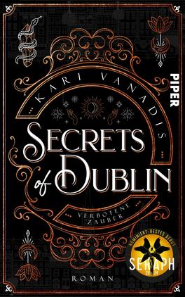 Secrets of Dublin: Verbotene Zauber Das Buchcover zeigt einen schwarzen Hintergrund mit goldenen und weißen dekorativen Elementen, darunter filigrane Muster und Symbole, die an Magie erinnern. In der Mitte steht in großen, eleganten Buchstaben der Titel „Secrets of Dublin“. Darunter befindet sich der Untertitel „Verbotene Zauber“. Der Autorname, Kari Vanadis, ist oben im Bogen platziert. In der unteren Ecke ist ein Auszeichnungssiegel mit der Aufschrift „SEKAPH 2021/22“ abgebildet. Die gesamte Gestaltung vermittelt eine mystische und geheimnisvolle Atmosphäre.