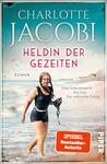 Das Buchcover zeigt eine Schwimmerin in einem Strandsetting, die entschlossen im Wasser steht. Der Hintergrund ist in sanften Blautönen gehalten und erzeugt eine ruhige Atmosphäre. Der Titel „Heldin der Gezeiten“ ist in großen, auffälligen roten Buchstaben mittig platziert, während der Autorenname „Charlotte Jacobi“ oben in eleganter Serifenschrift steht. Unter dem Titel befindet sich der Untertitel „Roman“ in kleinerer Schrift. Unten rechts ist der Hinweis „SPIEGEL Bestseller-Autorin“ in einem vertikalen Banner abgebildet.
