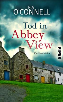 Tod in Abbey View Das Buchcover zeigt eine dramatische, wolkenverhangene Himmelsszenerie in verschiedenen Grautönen. Im Vordergrund sind mehrfarbige, historische Steinhäuser zu sehen, deren Fenster farblich hervorgehoben sind. Der Titel „Tod in Abbey View“ erscheint in großen, rot hervorgehobenen Buchstaben, während der Autorname „Pia O'Connell“ in einem schlichten weißen Schriftzug darüber platziert ist. Am unteren Rand des Covers befindet sich der Hinweis „Ein Irland-Krimi“ in kleinerer, blauer Schrift. Die Farben verleihen dem Cover eine geheimnisvolle und spannungsgeladene Atmosphäre.