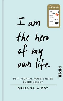 I Am The Hero Of My Own Life Das Buchcover zeigt einen hellblauen Hintergrund. In der Mitte befindet sich der Titel „I am the hero of my own life.“ in großen, handschriftlichen schwarzen Buchstaben. Darunter steht der Untertitel „Dein Journal für die Reise zu dir selbst“ in schlichter, grauer Schrift. Am oberen rechten Rand ist ein Sticker mit dem Text „Autorin des Weltbestellers“ sowie dem Hinweis „101 Essays, die dein Leben verändern werden“ platziert. Unten rechts ist das Verlagslogo „PIPER“ in schwarzer Schrift zu sehen.