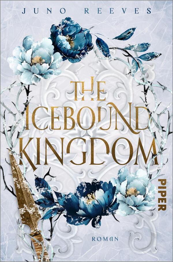 Das Buchcover zeigt eine elegante, frostige Hintergrundgestaltung in hellen Blautönen, umrahmt von floralen Elementen in verschiedenen Blautönen und eleganten, goldenen Akzenten. Im Zentrum der Gestaltung steht der Titel „THE ICEBOND KINGDOM“ in geschwungener, goldener Schrift, die den Eindruck von Luxus vermittelt. Darunter befindet sich der Autorenname „JUNO REEVES“ in schlichterer Schriftart. Das Cover strahlt eine geheimnisvolle und majestätische Atmosphäre aus, die zum Lesen anregt.