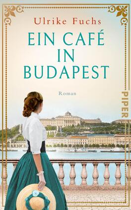 Ein Café in Budapest Das Buchcover zeigt eine Frau im historisierenden Kleid mit einer grünen Rockpartie und einer weißen Bluse, die mit dem Rücken zur Kamera steht. Sie betrachtet eine malerische Szenerie der Stadt Budapest, mit einem Blick auf das Ufer und markante Gebäude im Hintergrund. Der Himmel ist hell und klar. Oben auf dem Cover steht der Titel „EIN CAFÉ IN BUDAPEST“ in großen, türkisfarbenen Buchstaben, darüber der Name der Autorin Ulrike Fuchs. Am unteren Rand ist das Wort „Roman“ in kleinerer Schrift platziert.