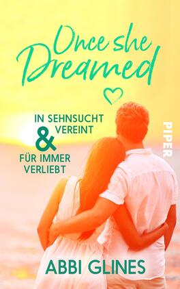 Once She Dreamed Das Buchcover zeigt ein romantisches Paar, das eng umschlungen steht, mit Blick auf einen hell erleuchteten Hintergrund in warmen Gelbtönen. Der Titel „Once she Dreamed“ ist in farbigen, kurvenreichen Buchstaben mittig platziert, umgeben von einem kleinen Herzsymbol. Darunter stehen die Sätze „IN SEHNSUCHT VEREINT“ und „FÜR IMMER VERLIEBT“ in einer klaren Schrift. Der Autorenname „Abbi Glines“ ist unten in einer schlichten Schriftart abgedruckt. Insgesamt vermittelt das Cover eine gefühlvolle, verträumte Atmosphäre.