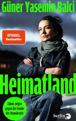 Heimatland Das Buchcover zeigt eine Porträtaufnahme einer Frau, die ernst in die Kamera blickt. Sie trägt einen schwarzen Winterjacke und eine graue Schal. Der Hintergrund ist in düsteren, graublauen Tönen gehalten, was eine nachdenkliche Stimmung erzeugt. Der Titel „Heimatland“ ist in großen, leuchtend grünen Buchstaben platziert. Darunter steht der Untertitel „Zähne zeigen gegen die Feinde der Demokratie“ in einer runden, grünen Blase. Der Autorinnenname „Güner Yasemin Balci“ ist oben auf dem Cover in schlichtem Weiß abgedruckt.