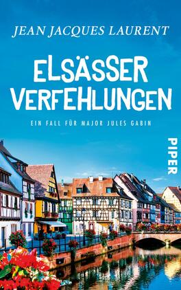 Elsässer Verfehlungen Das Buchcover zeigt ein malerisches Bild von bunten Häusern entlang eines Kanals in einer Stadt, die eine einladende Atmosphäre vermittelt. Der Himmel ist strahlend blau, während die Architektur typisch für das Elsass ist. Der Titel „ELSÄSSER VERFEHLUNGEN“ ist in großen, weißen Buchstaben prominent platziert. Darunter steht der Untertitel „Ein Fall für Major Jules Gabin“ in kleinerer Schrift. Das Verlagslogo „PIPER“ befindet sich in der rechten unteren Ecke.