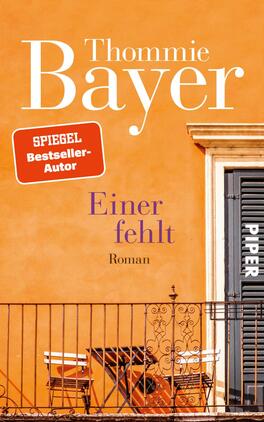 Einer fehlt Das Buchcover zeigt eine warme, orangene Wand im Hintergrund, vor der eine elegante Balkon-Szene abgebildet ist. Ein schwarzes Tor mit dem Schriftzug „PIPER“ ist gut sichtbar. In der oberen linken Ecke befindet sich ein rotes Feld mit der Aufschrift „SPIEGEL-Bestseller-Autor“. Der Titel „Einiger fehlt“ ist in einer geschwungenen, lila Schriftart platziert, darunter steht in kleinerer Schrift „Roman“. Die Gesamtatmosphäre vermittelt auf eine einladende und sonnige Stimmung.