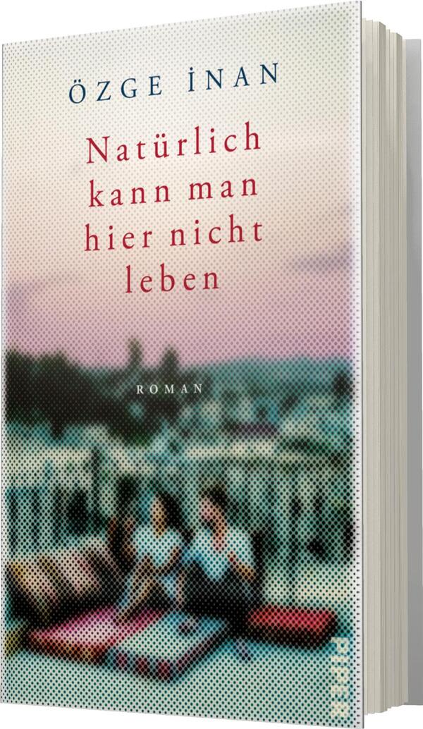 Das Buchcover zeigt eine unscharfe Darstellung von zwei sitzenden Frauen auf einem Balkon, umgeben von urbaner Szenerie. Der Hintergrund ist in sanften Pastellfarben gehalten, die an einen Sonnenuntergang erinnern, mit einer leicht verschwommenen Ansicht von Gebäuden. Der Titel „Natürlich kann man hier nicht leben“ ist in kräftigem Rot gesetzt, während der Autorenname „Özge İnan“ in einem dezenten Blau oben auf dem Cover steht. Der Untertitel „Roman“ ist in kleinerer Schriftgröße unter dem Titel platziert.