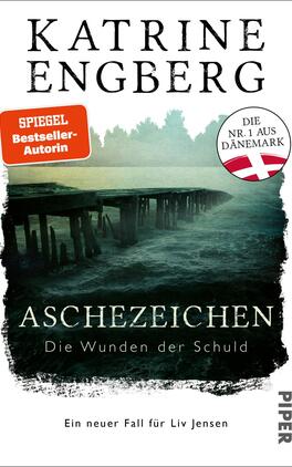 Aschezeichen Das Buchcover zeigt eine düstere Küstenlandschaft mit einem verwitterten Holzsteg, der ins graue, aufgewühlte Wasser führt. Das Hauptaugenmerk liegt auf dem Titel „ASCHEZEICHEN“ in großer, weißer Schrift, gefolgt von dem Untertitel „Die Wunden der Schuld“ in kleinerer, heller Schrift. Oben links befindet sich ein rotes Banner mit dem Text „SPIEGEL Bestseller-Autorin“. In der oberen rechten Ecke ist ein Kreissymbol mit der Aufschrift „DIE Nr.1 AUS DÄNEMARK“ in Weiß und Rot.