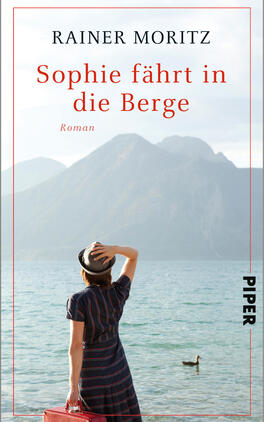 Sophie fährt in die Berge Das Buchcover zeigt eine Frau mit einem schwarzen Hut und einem gestreiften Kleid, die am Ufer eines Gewässers steht und lächelnd in die Ferne blickt. Im Hintergrund erheben sich majestätische Berge unter einem klaren Himmel. Der Titel „Sophie fährt in die Berge“ ist in auffälligem Rot oben auf dem Cover platziert, während der Name des Autors „Rainer Moritz“ in einer eleganten Schrift darüber steht. Am unteren Rand befindet sich der Verlagsname „PIPER“ in kleinerer Schrift. Die harmonische Farbgebung vermittelt eine einladende und entspannte Atmosphäre.
