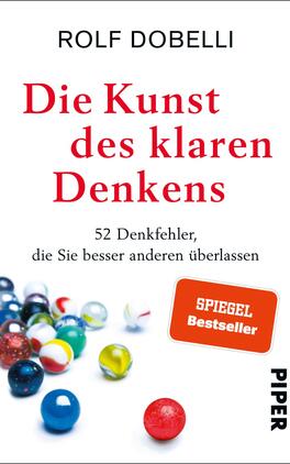 Die Kunst des klaren Denkens Das Buchcover zeigt auf einem hellen Hintergrund eine Ansammlung von bunten Murmeln in der unteren Bildhälfte. Der Titel „Die Kunst des klaren Denkens“ steht in großer roter Schrift zentral oben, gefolgt vom Autorennamen „Rolf Dobelli“ in schwarzer Schrift. Unter dem Titel befindet sich der Zusatz „52 Denkfehler, die Sie besser anderen überlassen“ in kleinerer Schrift. Oben rechts ist ein Siegel mit dem Aufdruck „SPIEGEL Bestseller“ in Weiß auf rotem Hintergrund. Unten links ist das Verlagslogo „PIPER“ in Schwarz.